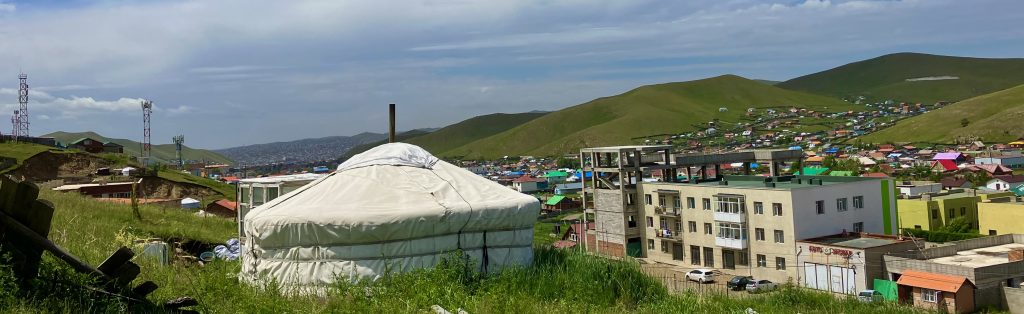 Mongolian Ger (which is a traditional yurt-style hut) with a backdrop of Ulaanbaatar suburbs.